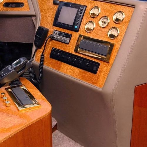 A control panel with various gauges and electronic devices, featuring a wood finish and a telephone. The setup appears to be part of a luxury vehicle or vessel interior.